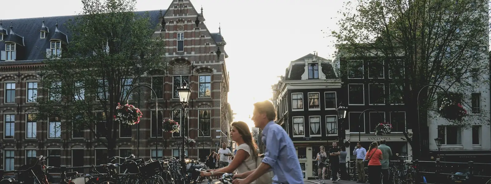 Couple cycling past Amsterdam canal houses